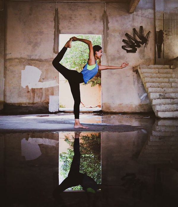 Woman practicing a gentle yoga pose in a calm, dark environment with mint-colored light.